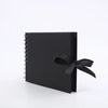 A black premium DIY scrapbook photo album with a black ribbon tied on the cover.