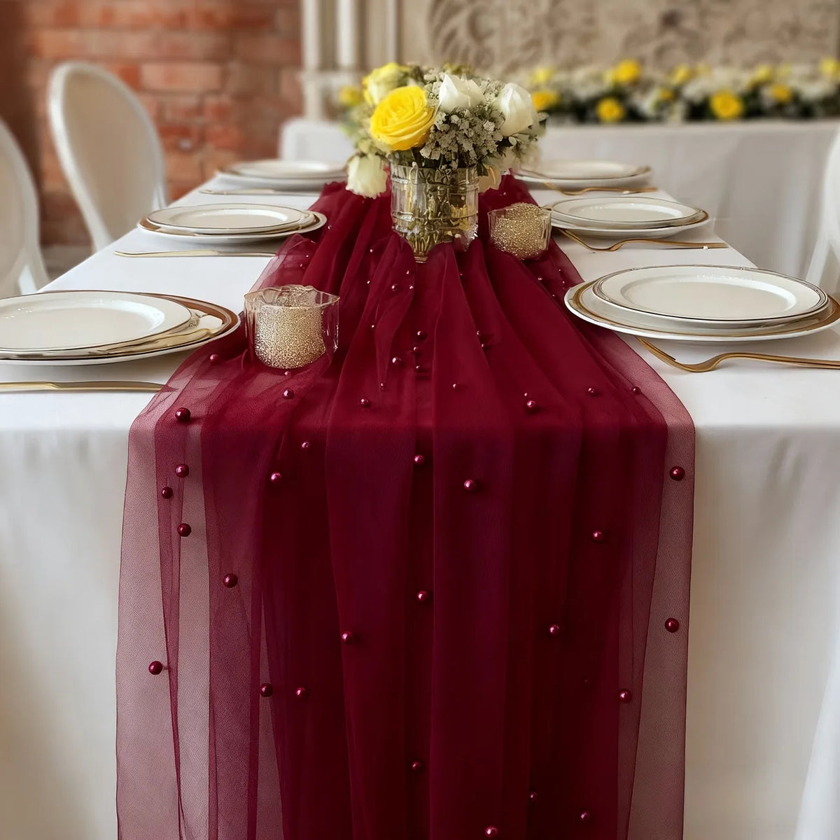 A deep burgundy pearl gauze table flag with beaded trim draped over a white tablecloth for an event.