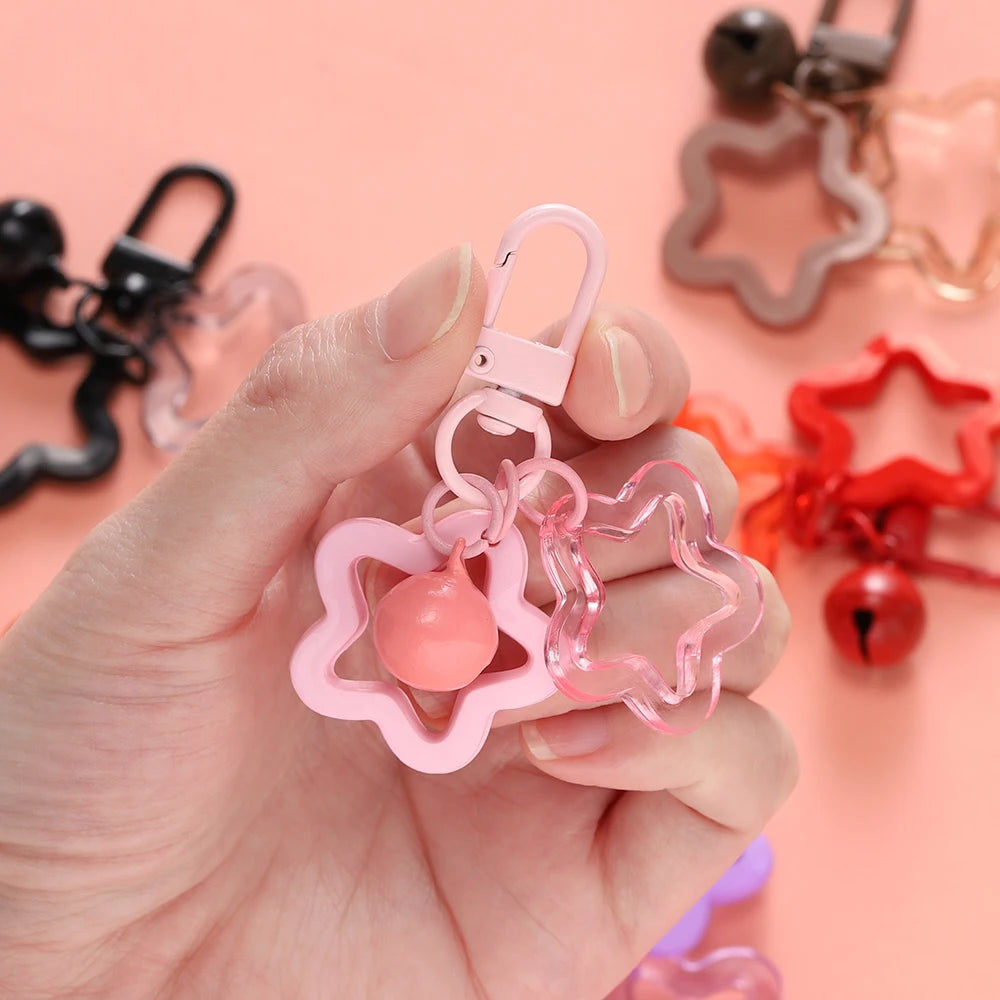 A hand holds a pink star charm pendant keychain with a pink bead and a clear star outline against a light pink background.
