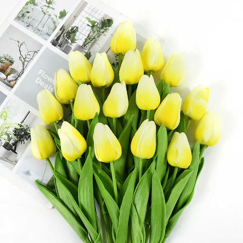 A bouquet of yellow artificial tulips with green stems and leaves.