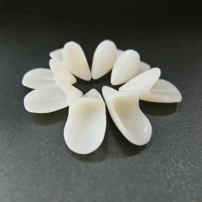 A set of realistic white vampire fangs with adjustable fit displayed on a dark surface.