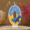 A birthday candle shaped like the number 0 featuring a blue dinosaur figure on a glittery blue and yellow background.