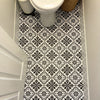 A close-up view of a bathroom floor with black and white Moroccan pattern stickers.