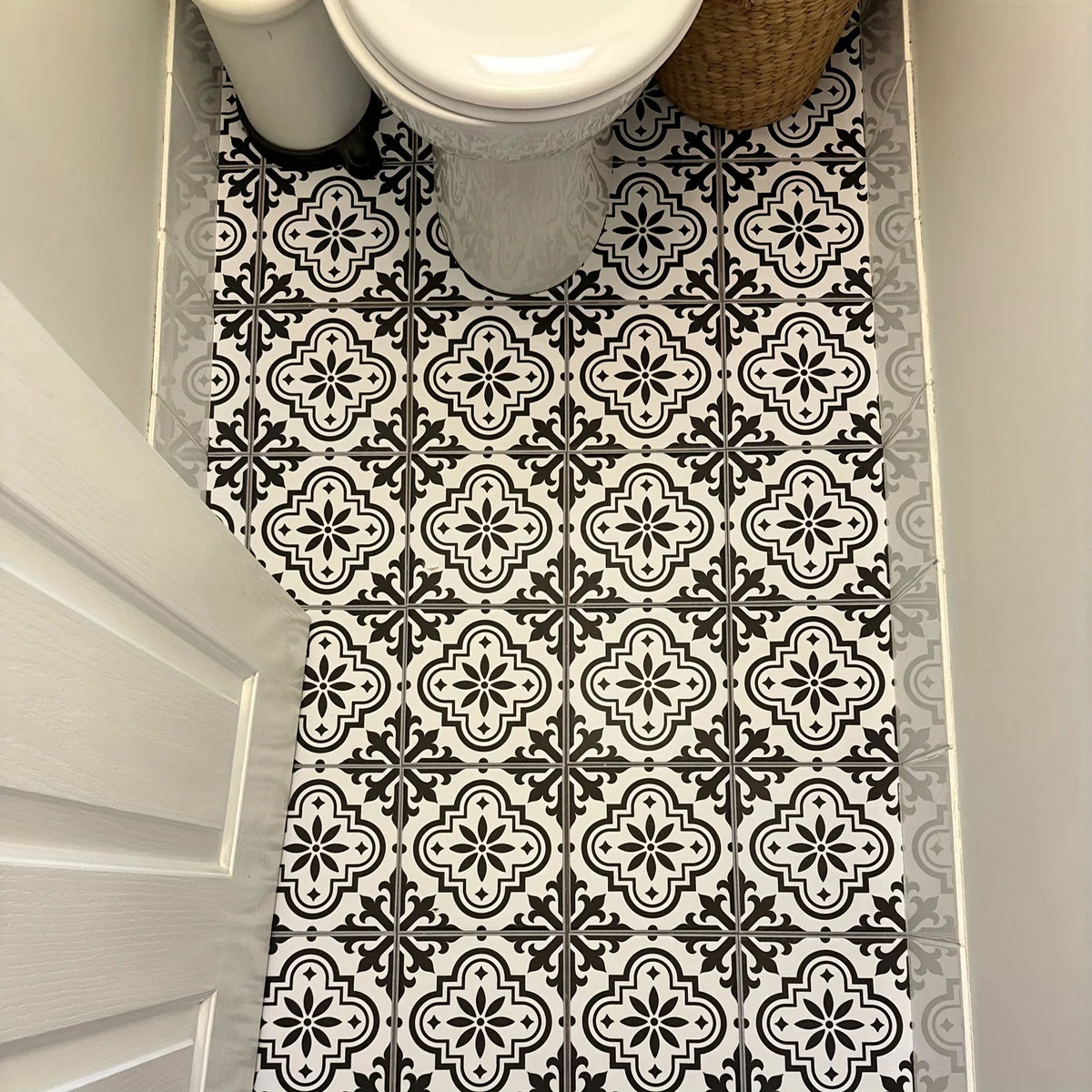 A close-up view of a bathroom floor with black and white Moroccan pattern stickers.