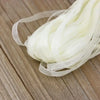 A bundle of white decorative fishtail yarn ribbon laid on a wooden surface.