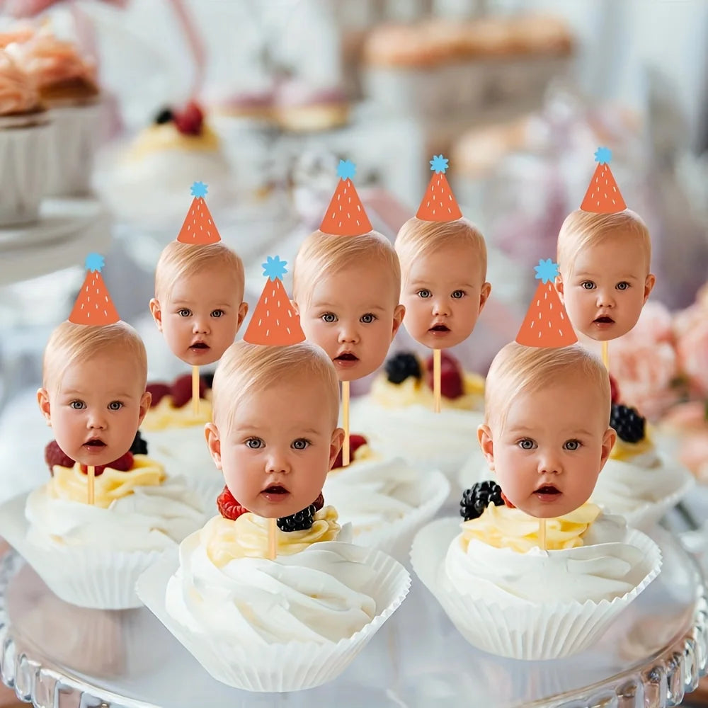 A display of white cupcakes topped with orange and blue conical toppers, arranged for a baby's first birthday party.