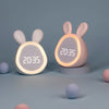 A pink bunny-shaped mini LED cartoon alarm clock night light with a glowing face display on a round stand.