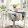 A white marble-printed tablecloth with gold and black ink textures is displayed on a table, featuring a pink teapot.