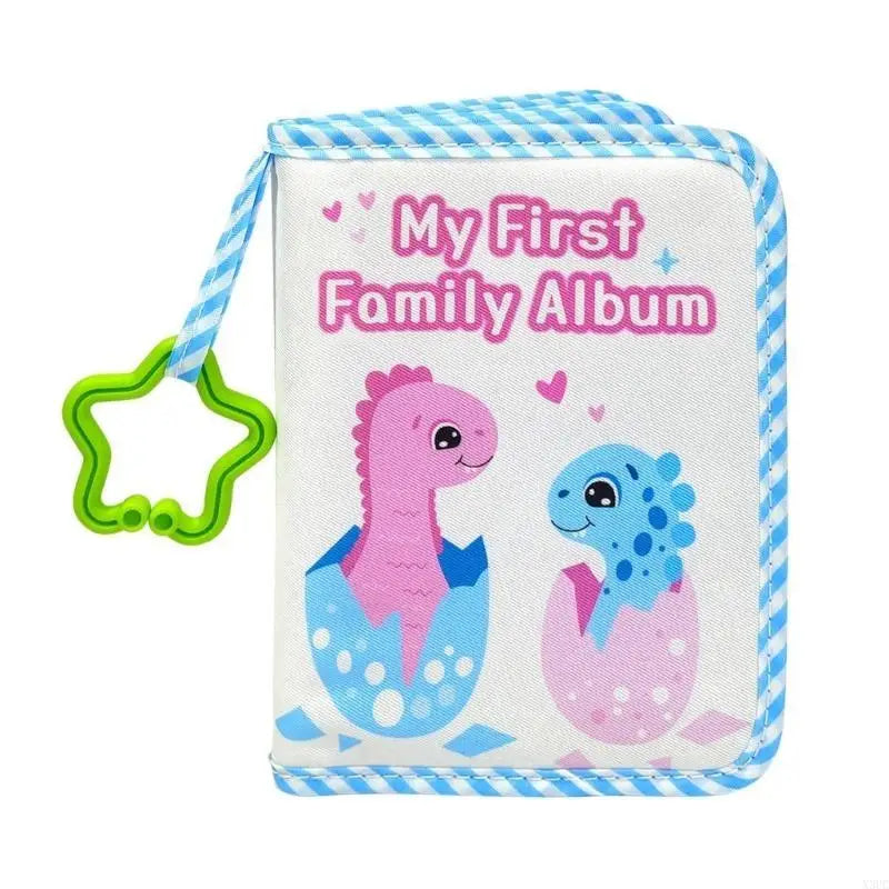 A pink cloth baby album with blue striped ribbon featuring the text My First Family Album and a purple dinosaur illustration.