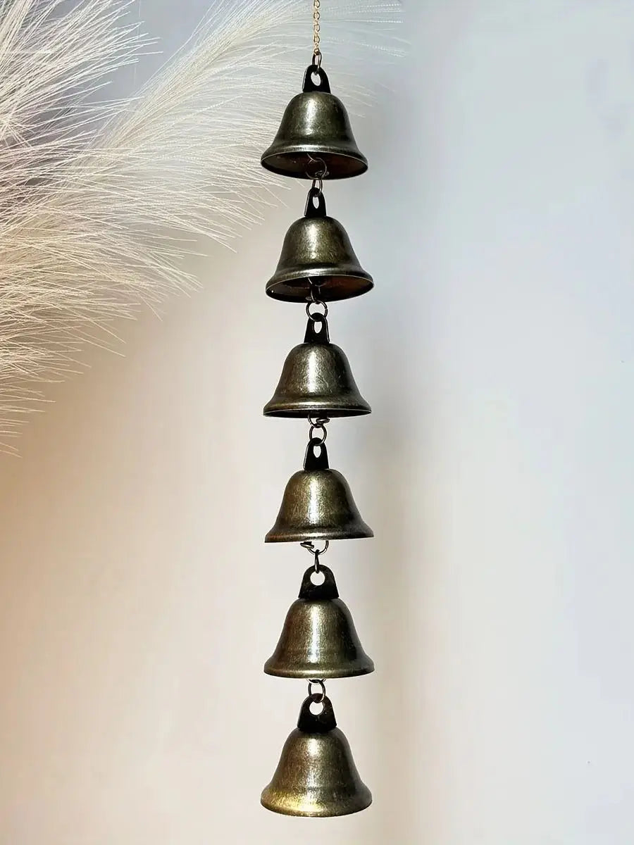 A vertical arrangement of five antique bronze metal wind chimes hanging against a white background.