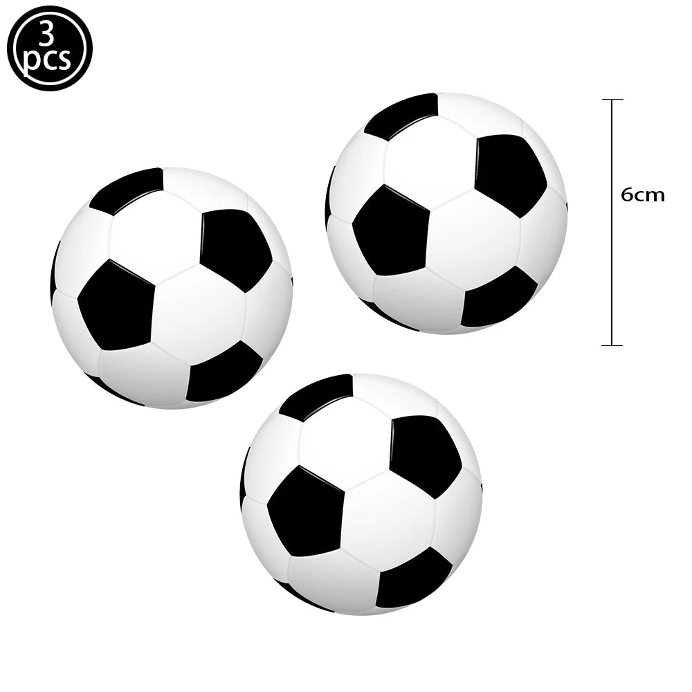 A set of three white and black soccer balls used as cake toppers.
