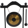 A black stand holding a brass gong decoration with hanging cords.