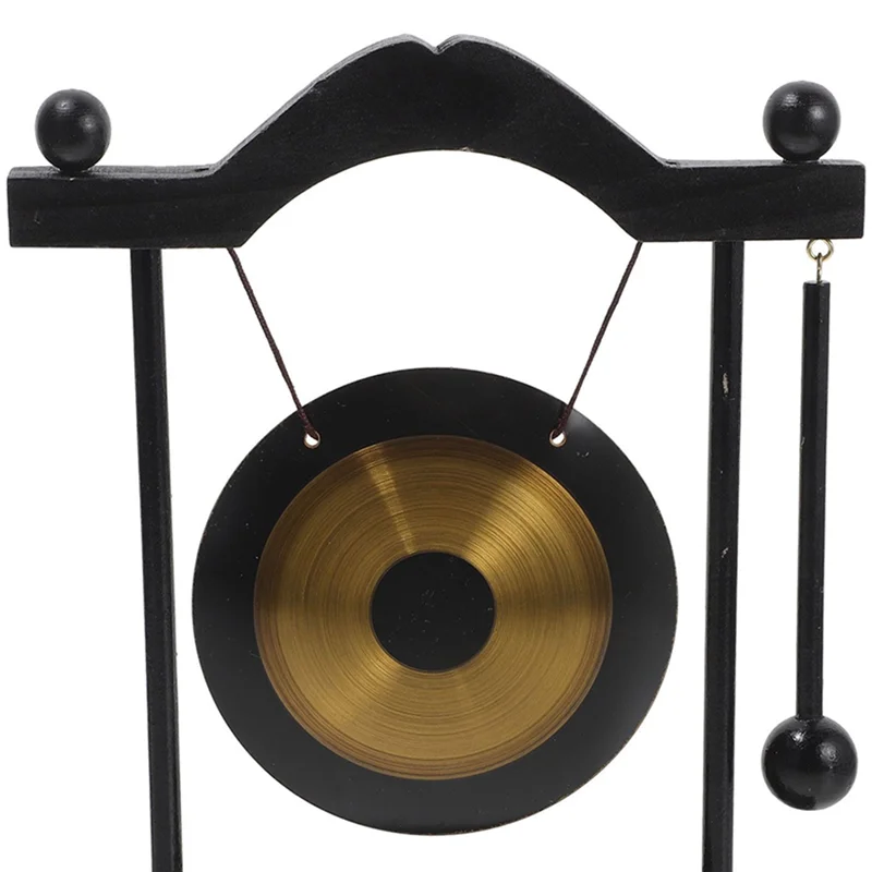 A black stand holding a brass gong decoration with hanging cords.