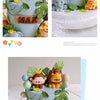 A tiered cake decorated with jungle animal toppers including a monkey, elephant, and lion.
