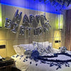 Marineblaue Geburtstagslitter, die 'happy birthday' schreiben, hängen über einem Bett
