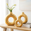 A golden Nordic geometric resin vase holding white tulips on a wooden table.