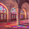 Interior view of an Islamic mosque with arched windows and colorful geometric patterns on the floor.