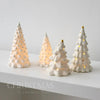 A display of white ceramic glow-in-the-dark mini Christmas tree decor in various sizes.