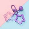A purple star charm pendant keychain with a silver clasp is displayed on a pink and blue background.