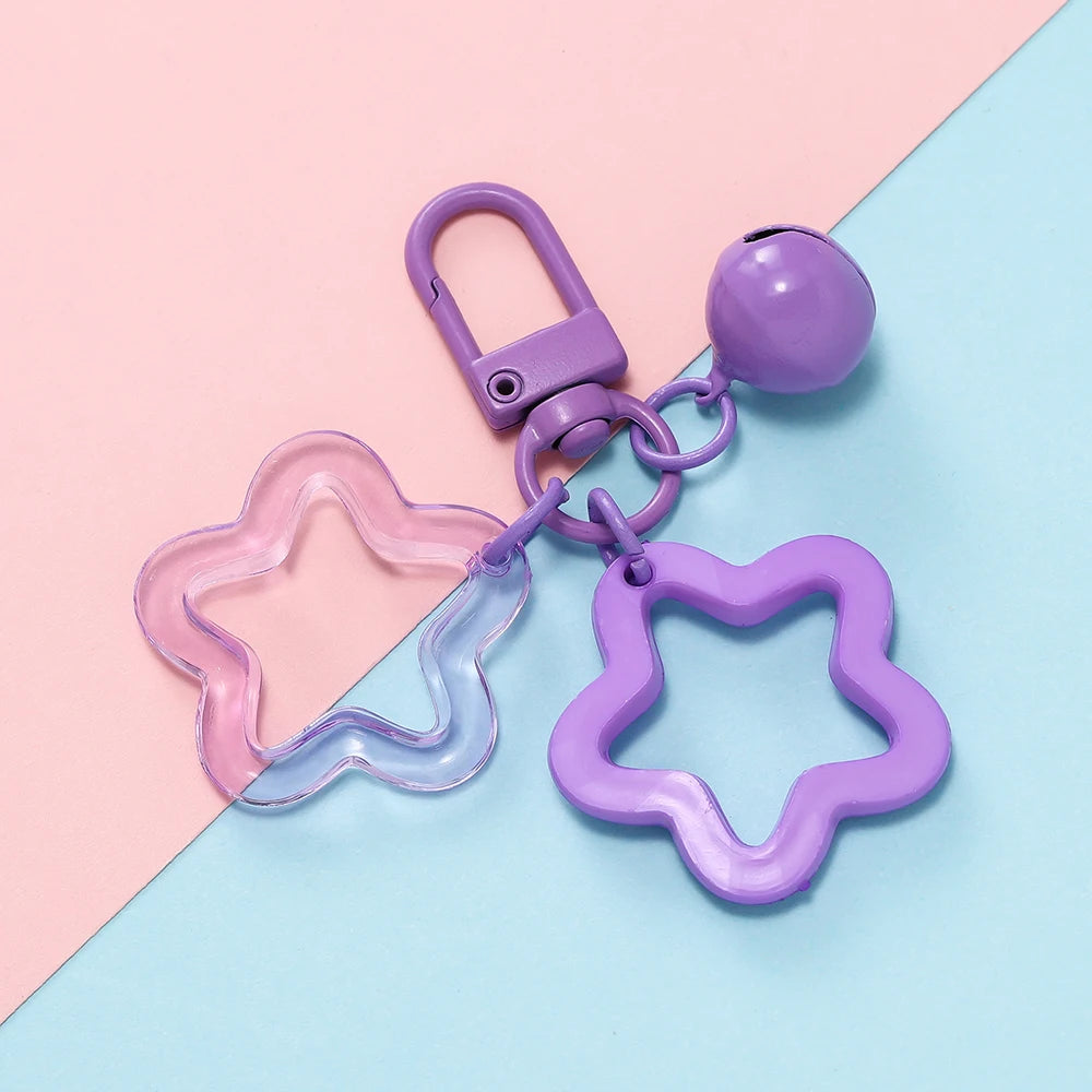 A purple star charm pendant keychain with a silver clasp is displayed on a pink and blue background.