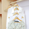 A set of space-saving hanger connector hooks is displayed on a wooden rack with white shirts hanging.