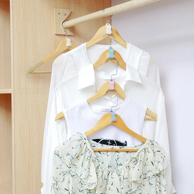 A set of space-saving hanger connector hooks is displayed on a wooden rack with white shirts hanging.