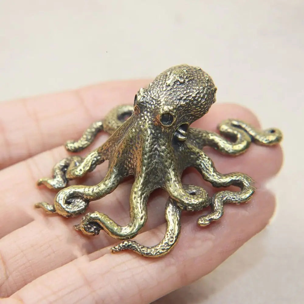Antique brass octopus desk ornament with textured body and flowing tentacles held in a hand.