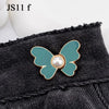 A teal butterfly button with a pearl center is attached to a black denim garment.