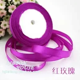 A roll of vibrant purple silk satin ribbon used for gift wrapping or decoration.