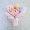 A handmade crochet sunflower mini bouquet featuring pink and yellow flowers tied with a white ribbon.