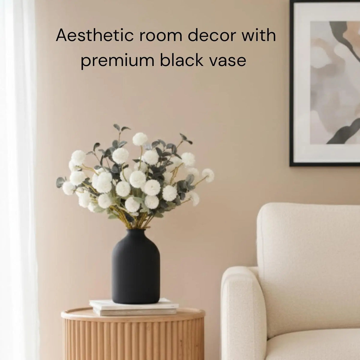 Aesthetic room decor featuring a large matte black vase filled with white flowers on a wooden table.