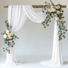 White sheer tulle draping fabric used to create a wedding arch backdrop with floral greenery
