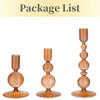 A set of three tapered glass candle holders in a warm amber tone.