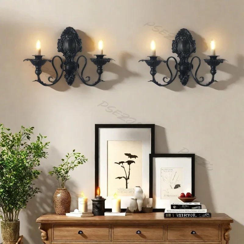 Vintage black wall pendant candle holders mounted above a wooden dresser with framed art.