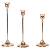 Set of three matte gold taper candle holders with slender metal stems and flared bases