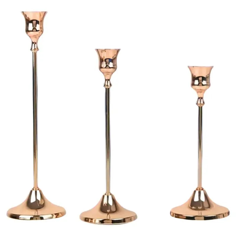 Set of three matte gold taper candle holders with slender metal stems and flared bases