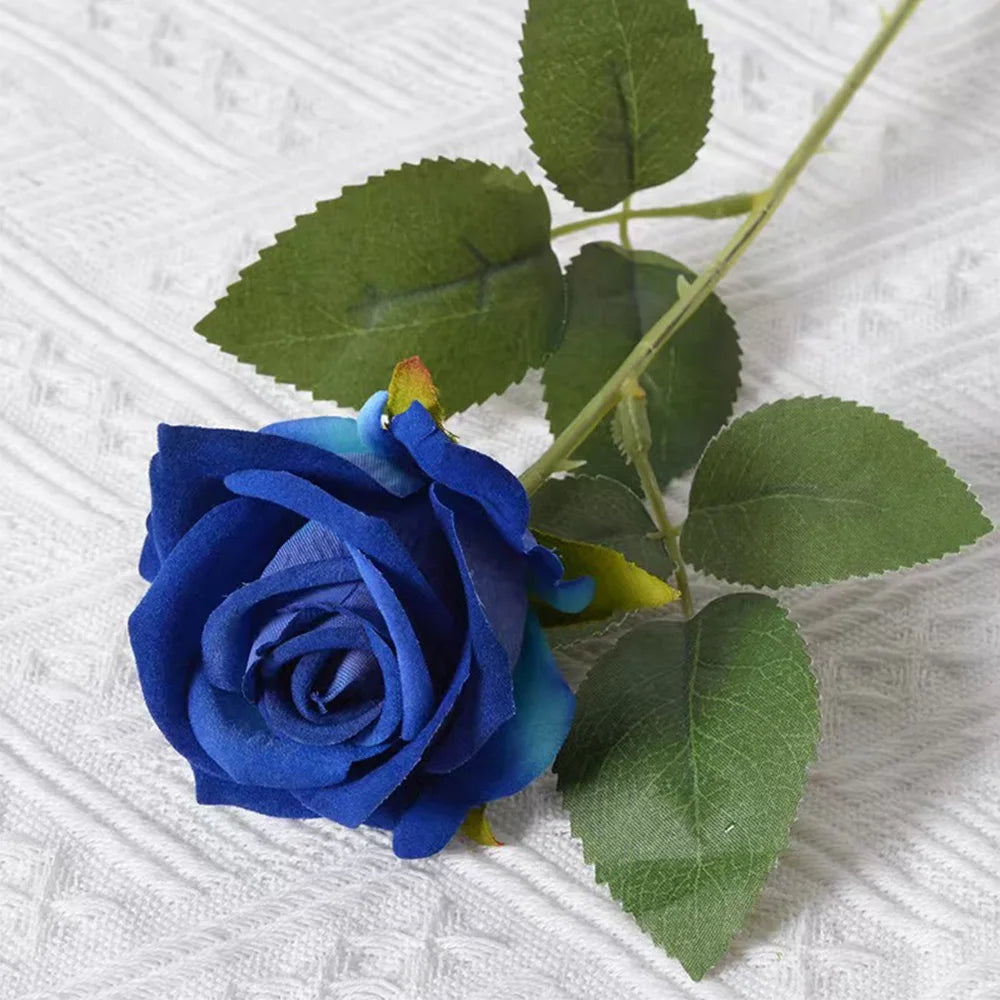 A deep blue artificial rose with green leaves on a stem, suitable for wedding or home decor.