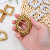 A hand holds a vintage gold mini picture frame surrounded by silver and gold frames on a woven mat.