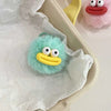 A light blue plush sausage-mouth keychain with large white eyes and a yellow mouth is shown in white tissue paper.