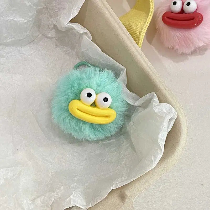 A light blue plush sausage-mouth keychain with large white eyes and a yellow mouth is shown in white tissue paper.