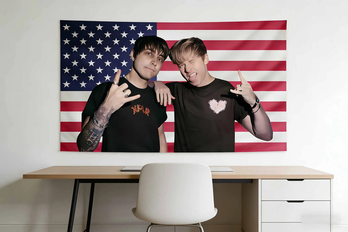 A man in a black shirt poses next to an American flag tapestry on a wall.