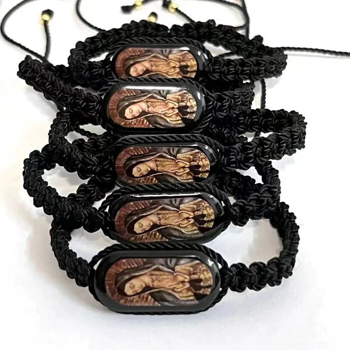 A black braided bracelet featuring multiple oval wooden charms depicting the Virgin Mary.