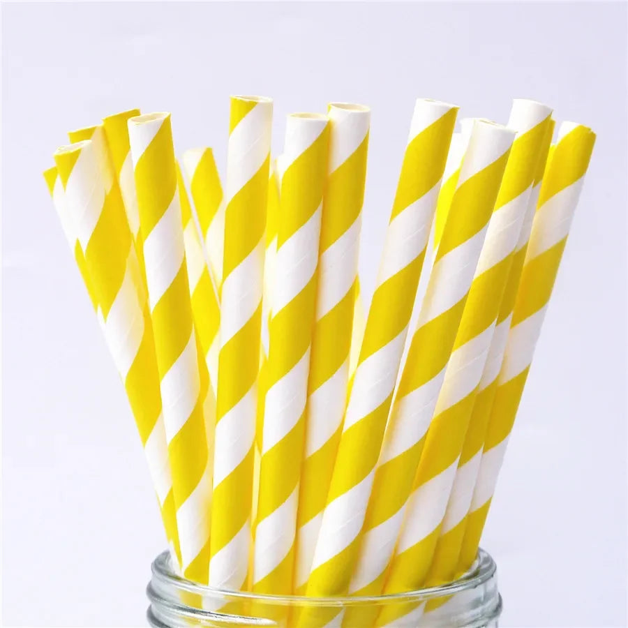 A bundle of yellow and white striped paper drinking straws is displayed in a glass container.