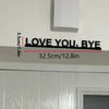 Black metal wall art sculpture with the text LOVE YOU BYE measuring 3.5cm or 1.4in wide
