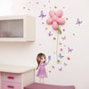 A young girl is standing in front of a white wall decorated with pink and purple butterfly stickers and a large pink flower b