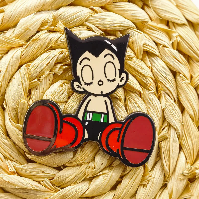 An enamel pin set featuring an animated character with black hair and large ears, depicted in a cute style.