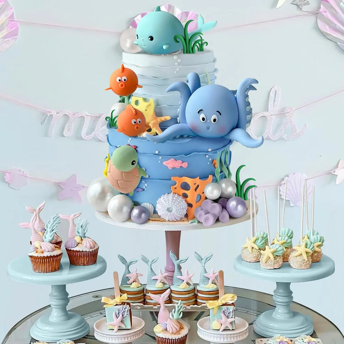 A tiered cake display featuring blue and orange sea animals, pearl balls, and decorative elements for a sea-themed party.