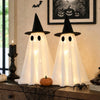 Dos figuras fantasma blancas LED con sombreros de bruja, exhibidas en una superficie de madera para decoración de Halloween