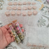 Mini glass bottles with cork stoppers filled with dried flowers and greenery for DIY crafts