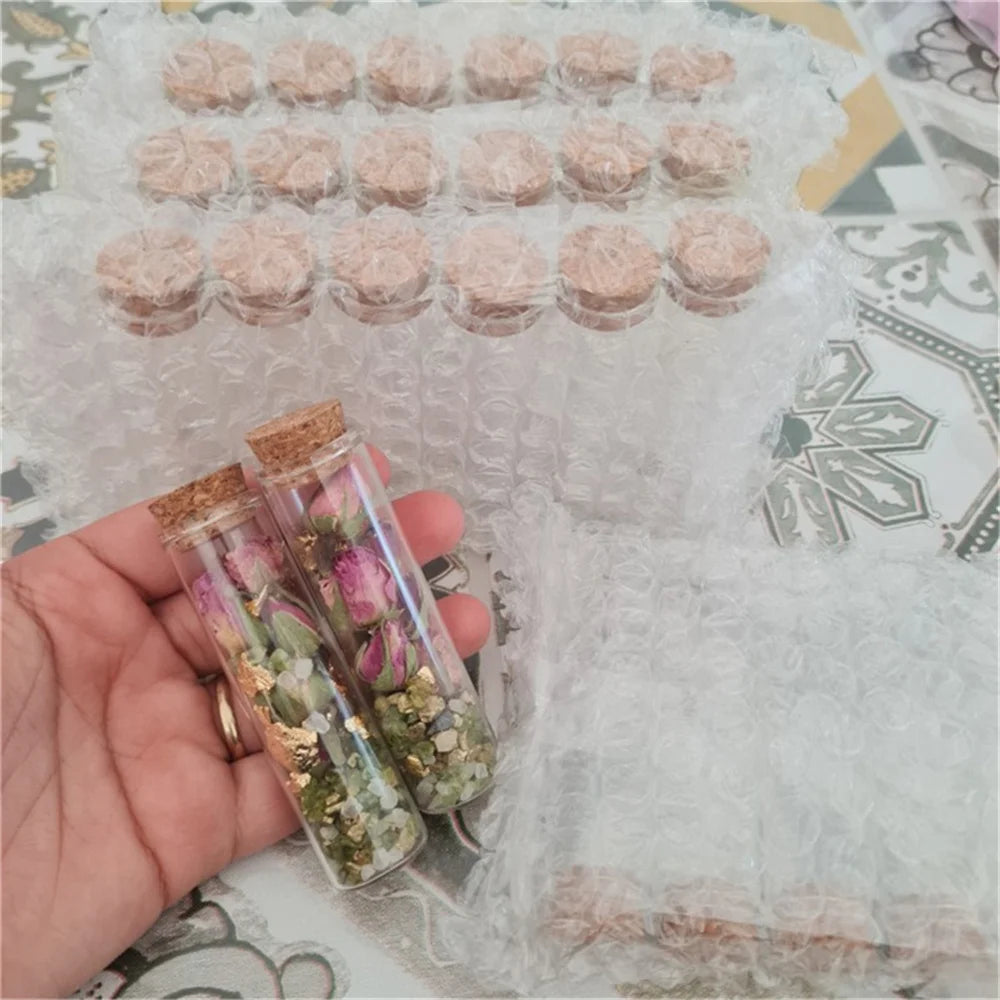 Mini glass bottles with cork stoppers filled with dried flowers and greenery for DIY crafts